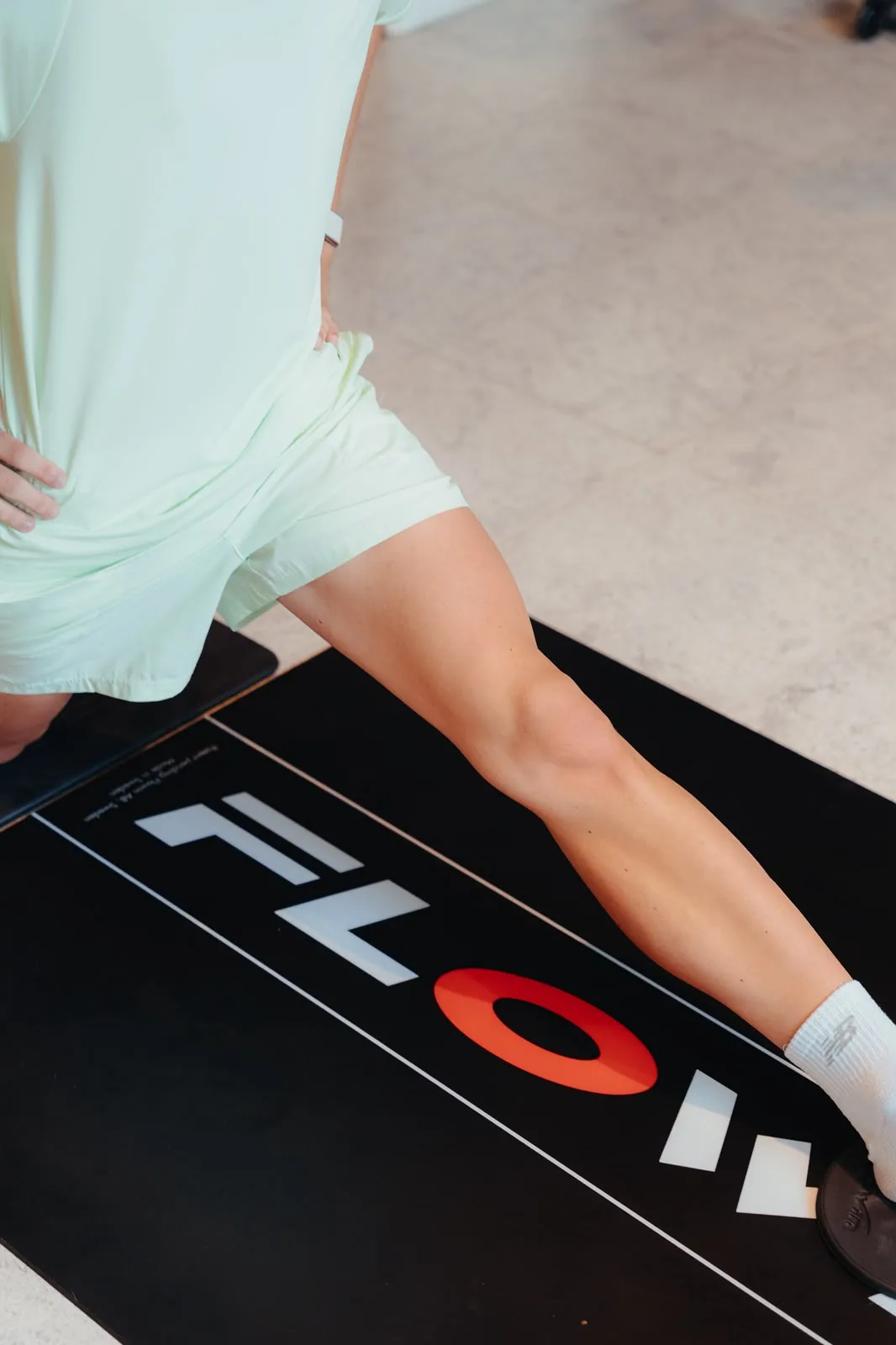 Jambes d'une personne en fente sur un tapis d'exercice noir.