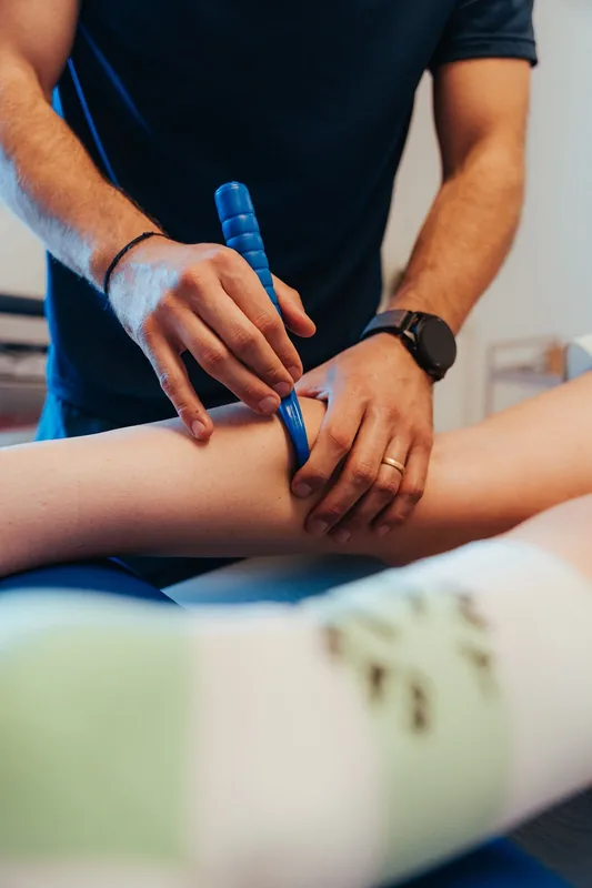 Kinésithérapeute utilisant un outil de gratage IASTM sur le mollet d'un patient