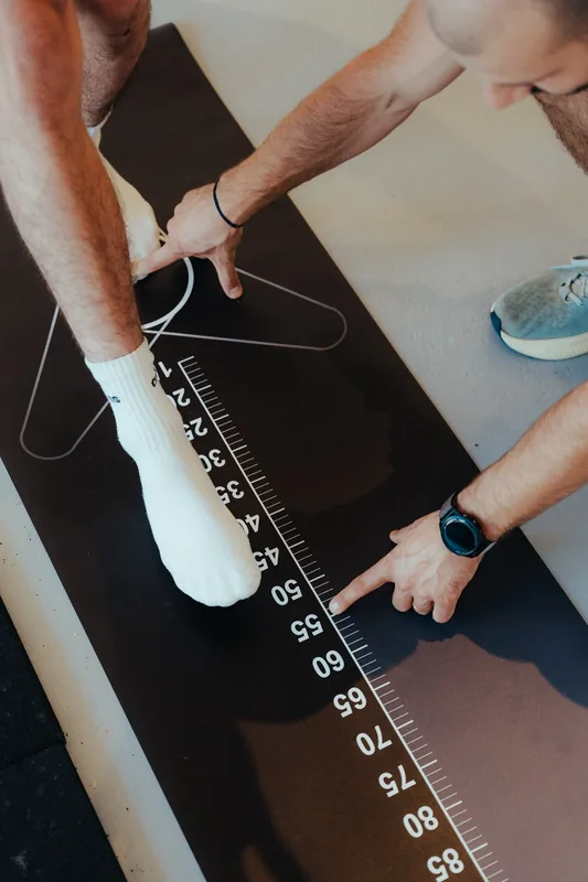 Kinésithérapeute mesurant la distance d'un saut sur un tapis gradué en centimètres